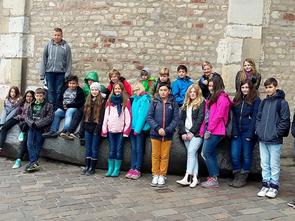 Klassenfoto vor der historischen Steinmauer.
